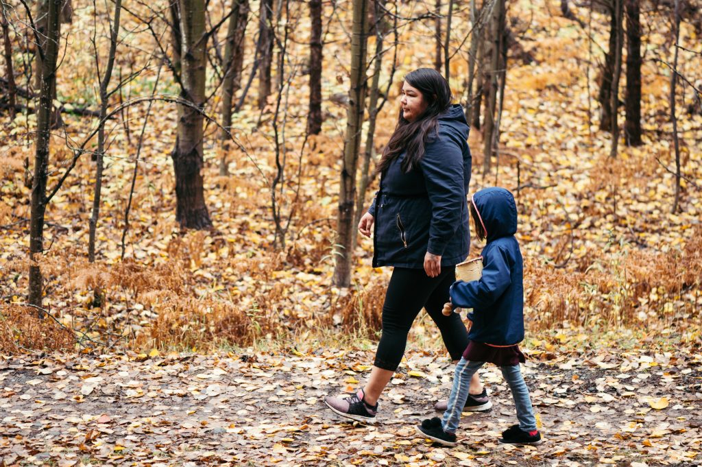 Une femme et son enfant marche sur un sentier couvert de feuille jaune. Il s'agit d'une belle représentation de l'automne en Abitibi-Témiscamingue. 