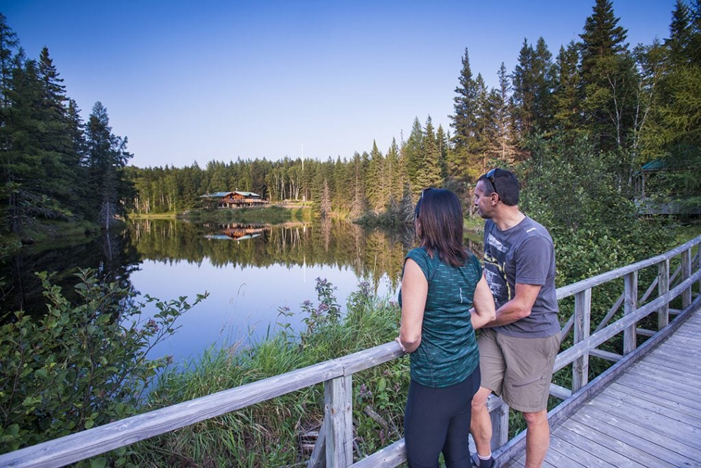 Couple sur le sentier La Castorière sur trottoir de bois regardant le lac et le poste d'accueil au parc national d'Aiguebelle