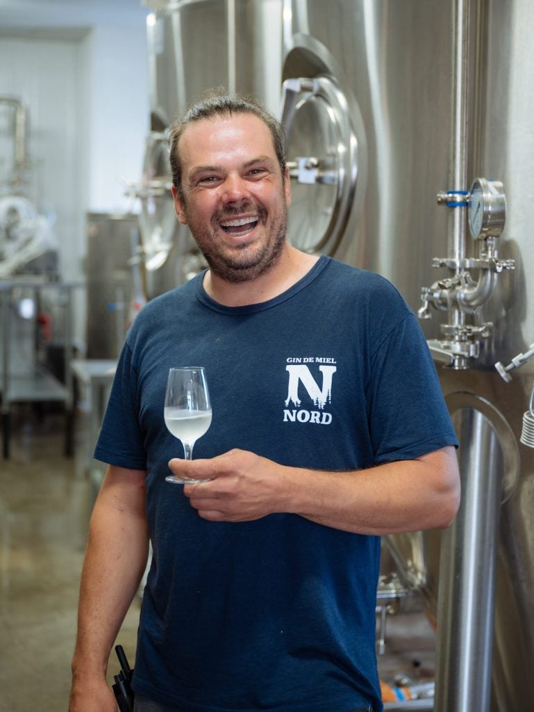 David Ouellet, mieillerie de la Grande Ourse avec un verre d'hydromel à la main à l'intérieur de la distillerie