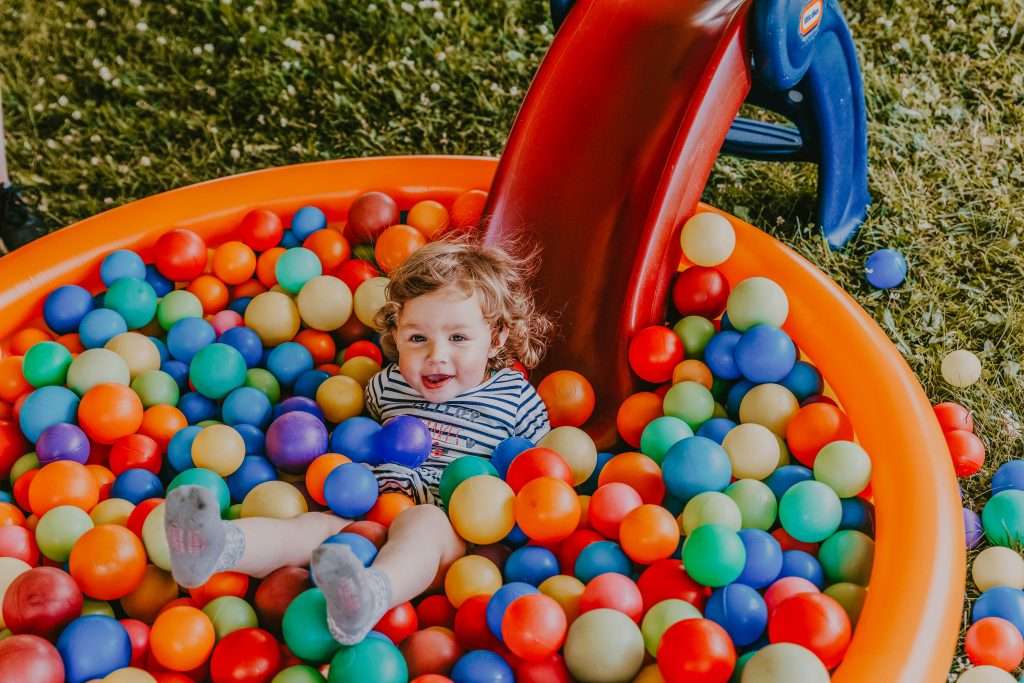 La photo présente un enfant jouant dans une piscine de boules multicolores.