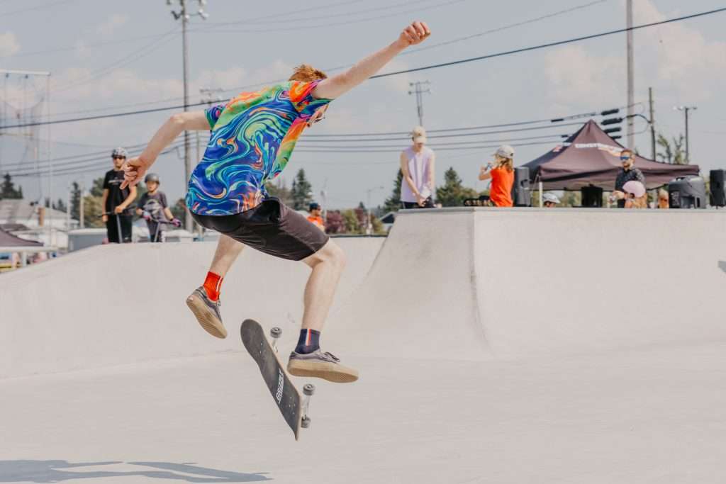 La photo présente un adolescent faisant des figure de skate.