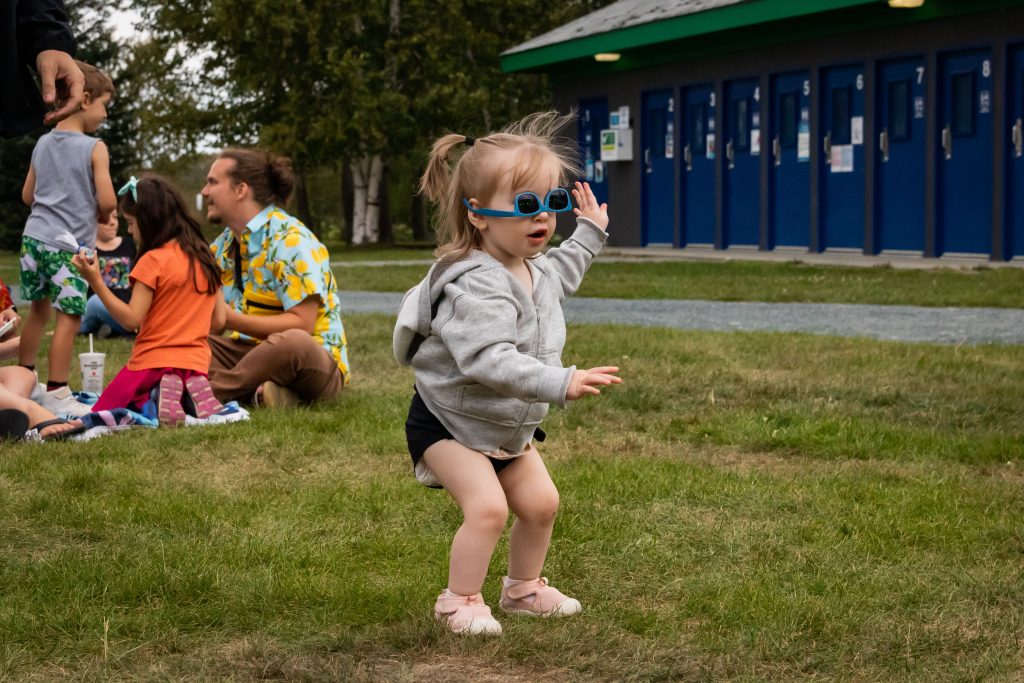 Une petite fille danse, avec des lunettes qu'elle porte à l'envers, lors du spectacle d'Elliot P. en collaboration avec l'ARLPHAT et Au Pays des pick-up. 