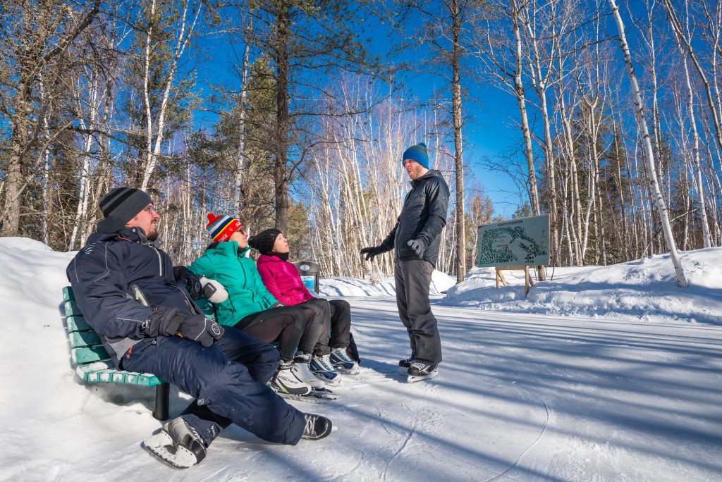 Des patineurs prennent une pause sur un banc dans le sentiers Agnico Eagle de la Forêt récréative de Val-d'Or. 